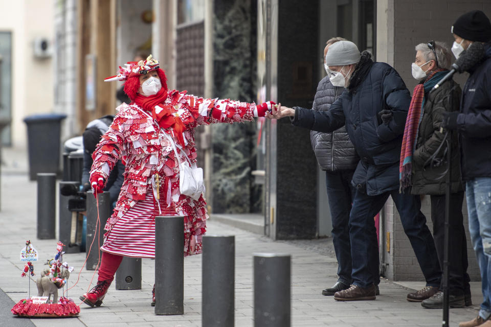 CORRECTS THE DATE - Kiki Neumann walks in disguise along the route taken by the carnival parade Rosenmontagszug and delivers candies to spectators in Cologne, Germany, Monday, Feb. 15, 2021. Because of the coronavirus pandemic the traditional carnival parades are canceled. (Marius Becker/dpa via AP)