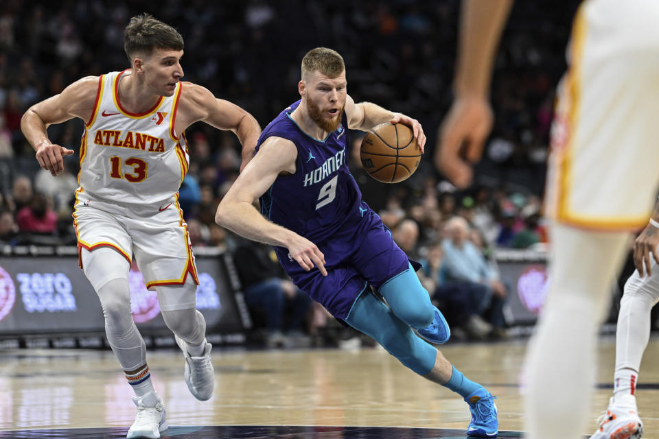 Charlotte Hornets forward Davis Bertans (9) drives past Atlanta Hawks guard Bogdan Bogdanovic (13) during the first half of an NBA basketball game Wednesday, Feb. 14, 2024, in Charlotte, N.C. (AP Photo/Matt Kelley)