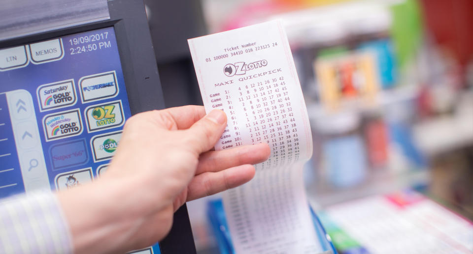 A man holds an Oz Lotto ticket in a newsagent. 