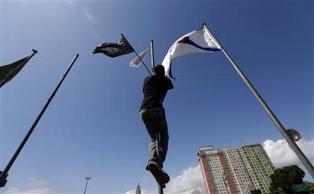 A demonstrator from the group called Black Bloc climbs with a black flag in place of the Rio de Janeiro state flag during a protest on Brazil's Independence Day in Rio de Janeiro September 7, 2013. REUTERS/Ricardo Moraes