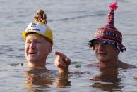 Members of the Berliner Seehunde (Berlin Seals) ice swimmers club take a dip in Lake Orankesee during their traditional New Year swimming event in Berlin, January 1, 2015. The words on the helmet (L) reads "The Berlin Brandenburg international airport BER is totally unsuccessful." REUTERS/Fabrizio Bensch (GERMANY - Tags: SOCIETY SPORT SWIMMING)