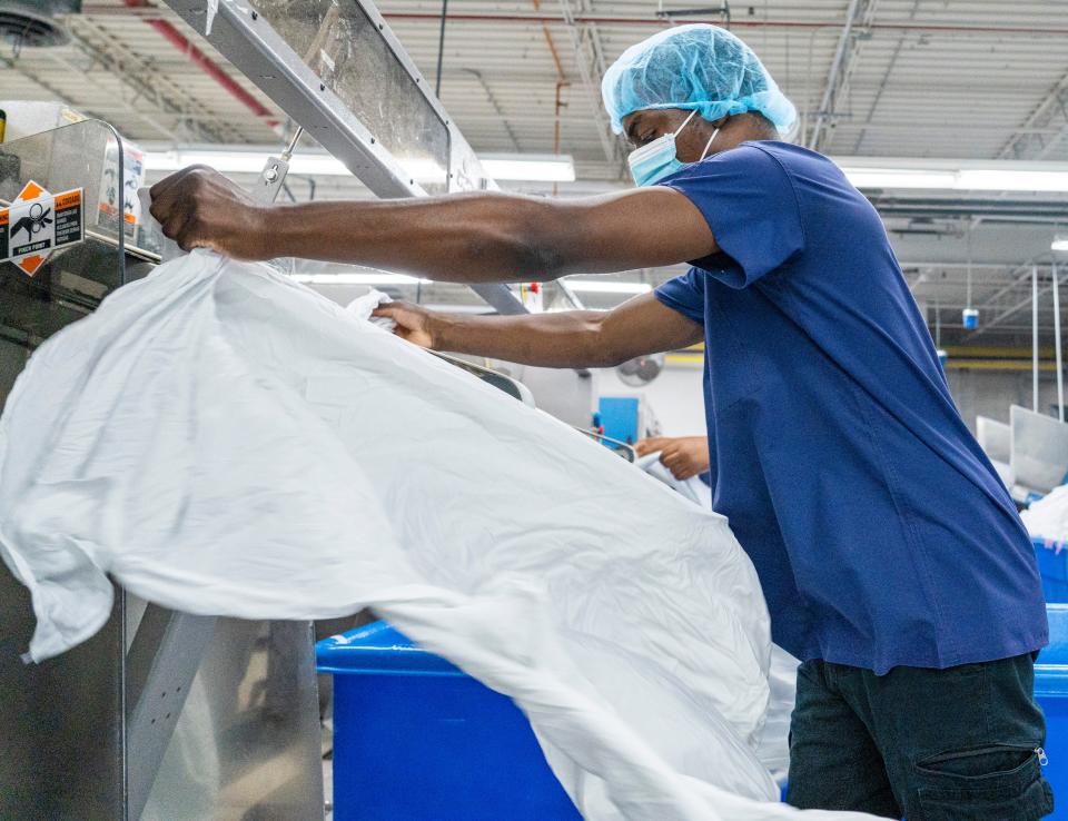 Utility worker Nyjel Farrington feeds linens through an automatic folder at one of the largest laundry facilities in Wisconsin, providing laundry and linen services for hospitals, clinics, nursing homes and the military throughout Wisconsin and Northern Illinois on Tuesday, June 28, 2022 at the Goodwill's James O. Wright Center for Work & Training in Milwaukee, Wis.