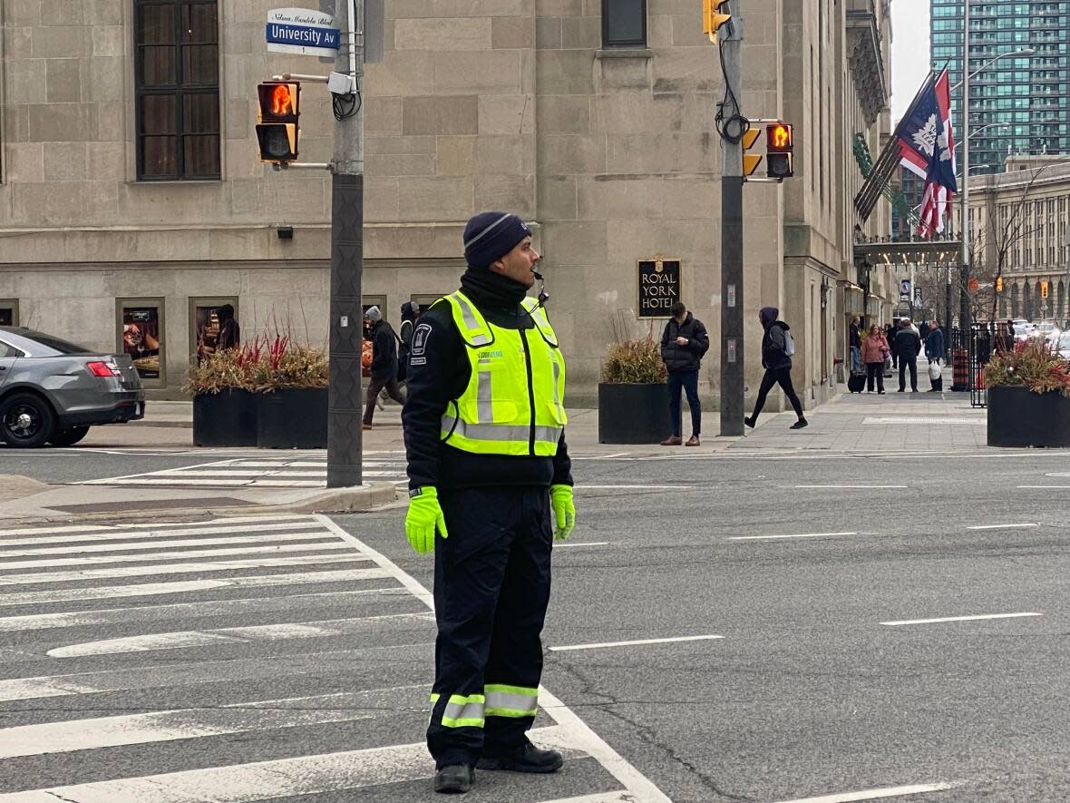 A traffic agent directs vehicles at Front Street and University Avenue in Toronto on April 18, 2023. The City announced Tuesday that it will expand the program to tackle traffic congestion and increase road safety.  (Talia Ricci/CBC - image credit)