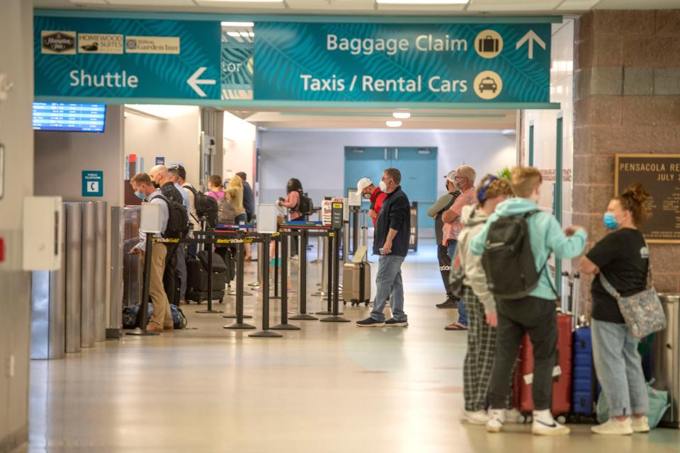 Passengers pick up the baggage at baggage claim at Pensacola International Airport Sunday, April 3, 2022.