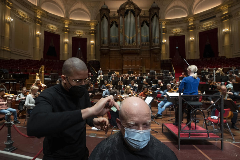 People get a haircut during a rehearsal at the Concertgebouw in Amsterdam, Wednesday, Jan. 19, 2022, as Dutch museums, theaters and concert halls played host Wednesday to businesses that are allowed to open to customers as a protest against their own continuing lockdown closures. (AP Photo/Peter Dejong)