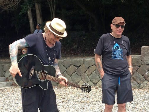 In this Monday, Sept. 1, 2013 photo released by Dolphin Project, former Guns N' Roses drummer Matt Sorum, left, plays the guitar in front of Ric O’Barry, right, and Japanese anti-dolphin hunt activists on a beach in Taiji, central Japan. Sorum was in the remote Japanese fishing village Monday to protest against its annual dolphin hunt. Sorum, who now leads his own group, is the latest celebrity to join the increasingly global campaign to stop the dolphin kill in Taiji, a quaint fishing village made famous by O'Barry's Academy Award-winning 2009 film about the hunt called "The Cove." (AP Photo/Dolphin Project)