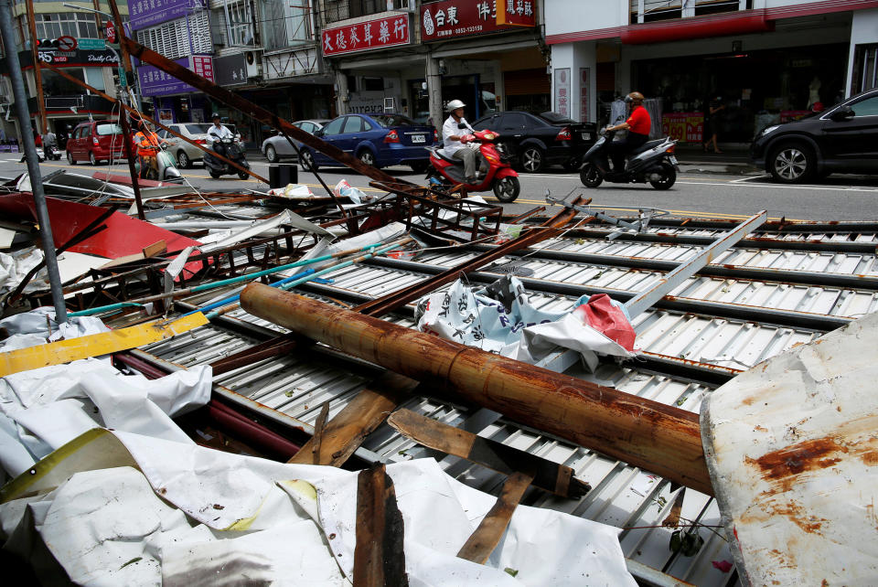 Motorcyclists ride past damage by Typhoon