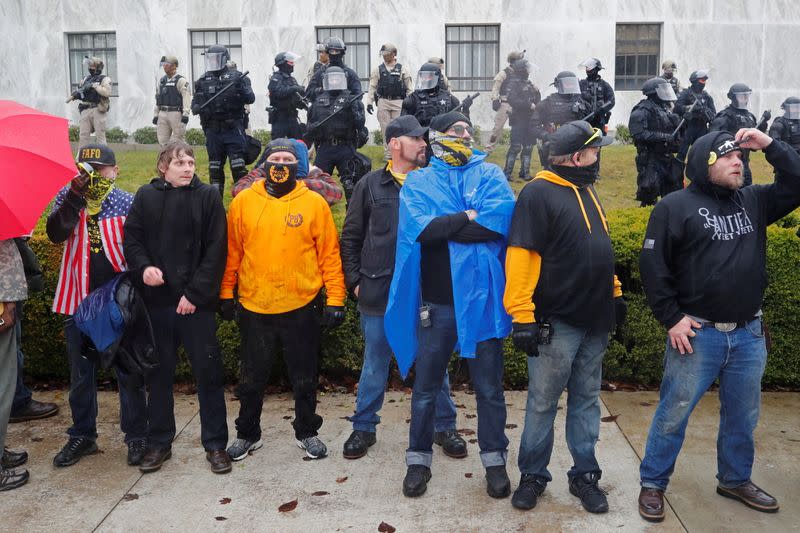 Members of the Proud Boys stand in front of police at a rally in support of U.S. President Donald Trump at the Oregon State Capitol in Salem