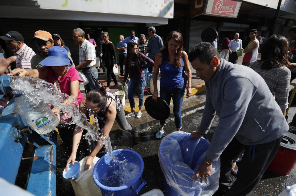 People collect water from a truck that delivers water during rolling blackouts, in Caracas, Venezuela, Tuesday, March 12, 2019. The blackout marked another harsh blow to a country paralyzed by turmoil as the power struggle between Venezuelan President Nicolas Maduro and opposition leader Juan Guaido stretches into its second month and economic hardship grows. (AP Photo/Eduardo Verdugo)