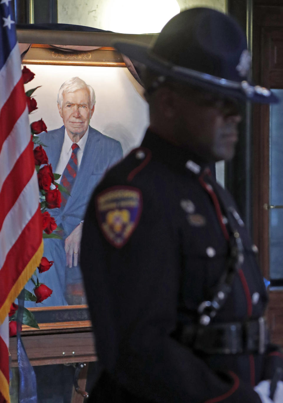 A portrait of the late Republican senator Thad Cochran, is visible behind a member of the Mississippi Highway Patrol honor guard, during his funeral service in the Mississippi State Capitol rotunda in Jackson, Miss., Monday, June 3, 2019. Cochran was 81 when he died Thursday in a veterans' nursing home in Oxford, Miss. (AP Photo/Rogelio V. Solis)