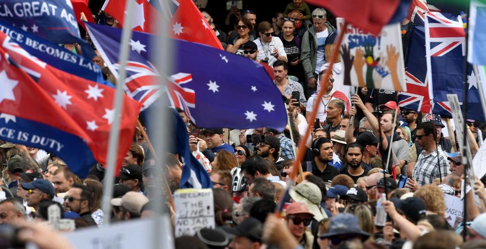 Protesters are seen past flags during a rally against new pandemic laws and vaccination mandates in Melbourne.