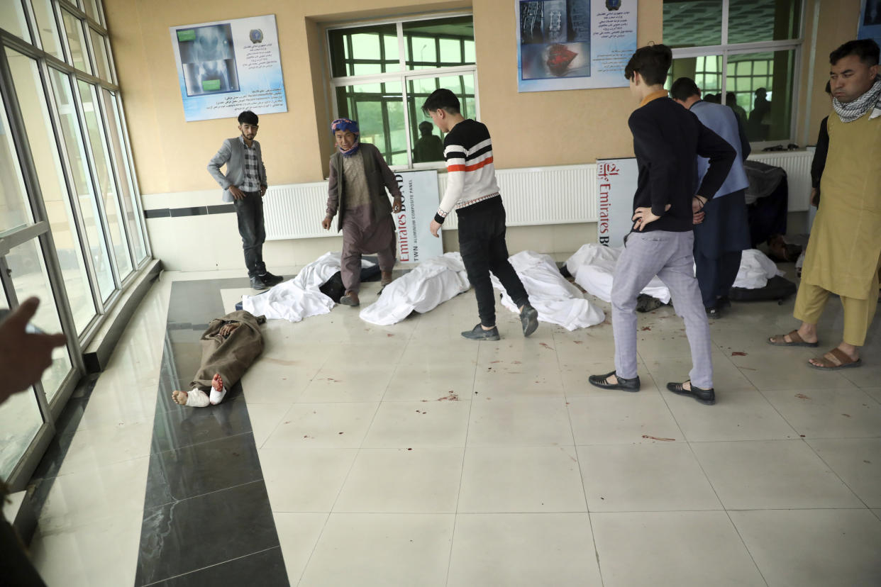 Afghan men try to identify the dead bodies at a hospital after a bomb explosion near a school west of Kabul, Afghanistan, Saturday, May 8, 2021. A bomb exploded near a school in west Kabul on Saturday, killing several people, many them young students, an Afghan government spokesmen said. (AP Photo/Rahmat Gul)