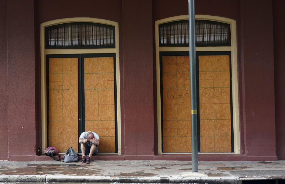 A man sits in front of a French Quarter business with windows boarded in preparation Hurricane Ida, Saturday, Aug. 28, 2021, in New Orleans,. (AP Photo/Eric Gay)