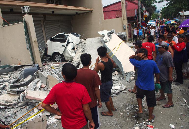 People look at a collapsed building in Cebu City, Philippines after a major 7.1 magnitude earthquake struck the region on October 15, 2013