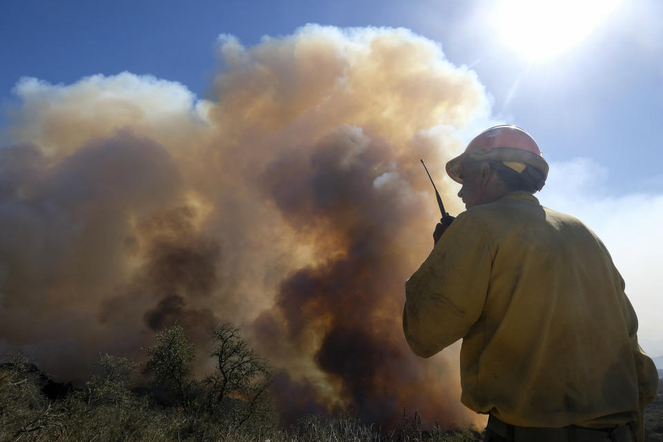 FILE - In this Oct. 13, 2021, file photo, a firefighter watches as smoke rises from a wildfire in Goleta, Calif. Worsening climate change requires that the United States do much more to track and manage flows of migrants fleeing natural disasters. That's the finding of a multiagency study from the Biden administration. President Joe Biden ordered the assessment. (AP Photo/Ringo H.W. Chiu, File)