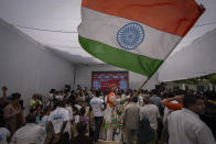 A Congress party supporter waves an Indian flag as others follow proceedings of vote counting on a giant screen at their party headquarters in New Delhi, India, Tuesday, June 4, 2024. India was counting more than 640 million votes cast over the past six weeks in the world’s largest democratic exercise, which was widely expected to give Prime Minister Narendra Modi a third five-year term when the final result is declared later Tuesday. (AP Photo/Altaf Qadri)