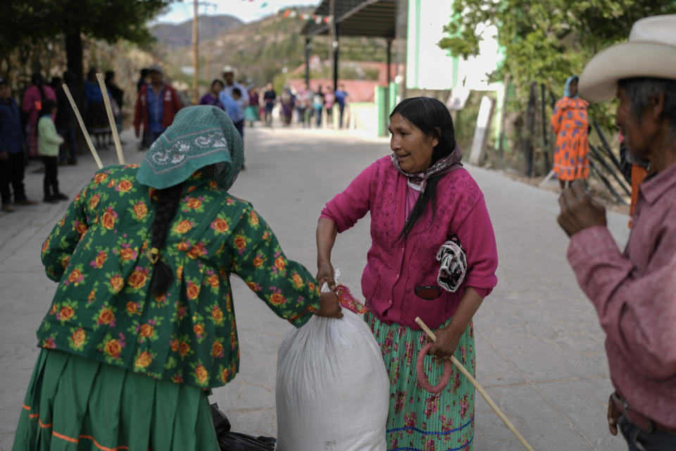 Una mujer rarámuri, a la izquierda, que representa al equipo en la competencia de carreras de Arihueta, recoge sus ganancias del representante del equipo contrario, en Cuiteco, México, el sábado 11 de mayo de 2024. (AP Foto/Eduardo Verdugo)