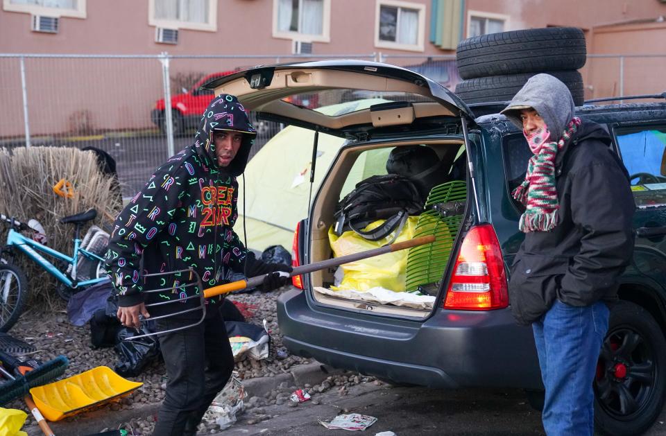 Venezuelan migrant Rodney Rodriquez, 31, left, loads lawn-care equipment into his car as city officials clear out an illegal tent encampment in Denver on Wednesday, Jan. 3, 2024