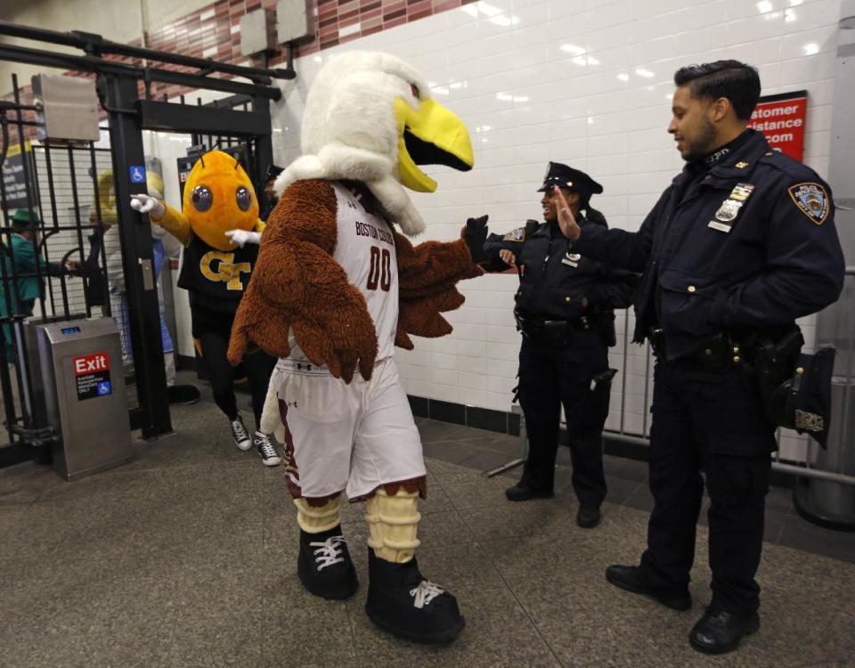 Boston College's "Baldwin the Eagle," mascot, trades high fives with New York City police officers as he and Georgia Tech's mascot "Buzz," left, enter the subway, Monday, March 6, 2017, in New York, before they and 13 other mascots rode the subway in downtown Brooklyn to promote the Atlantic Coast Conference Basketball tournament. The tournament, which involves 15 schools, will be played March 7-11 at the Barclays Center in Brooklyn. (AP Photo/Kathy Willens)