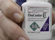 FILE - In this April 2, 2018, file photo, a pharmacist in San Francisco poses for photos holding a bottle of OxyContin. In court papers filed in New York on Sunday, Sept. 15, 2019, Purdue Pharma, the drug's manufacturer, flied for Chapter 11 bankruptcy protection. (AP Photo/Jeff Chiu, File)
