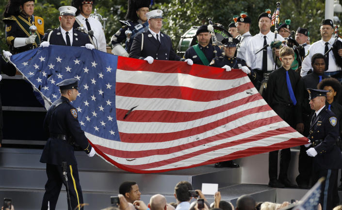 New York City firefighters and police officers hold a damaged flag from the World Trade Center site during ceremonies marking the 10th anniversary of the 9/11 attacks on the World Trade Center, in New York September 11, 2011. (REUTERS/Larry Downing)