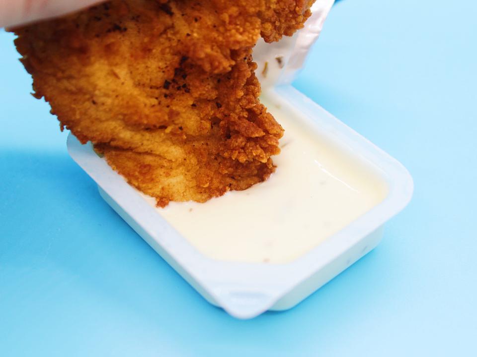 chick fil a chicken tender dipped in ranch sauce on blue background