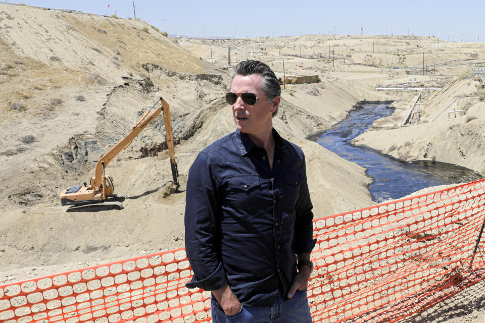 FILE - California Gov. Gavin Newsom tours the Chevron oil field west of Bakersfield where a spill of more than 800,000 gallons flowed into a dry creek bed in McKittrick, Calif., on July 24, 2019. Gov. Newsom has changed plans and won't be going to the upcoming United Nations Climate Change Conference in Glasgow, Scotland. Newsom's office cited "family obligations" as the reason. (Irfan Khan/Los Angeles Times via AP, Pool, File)