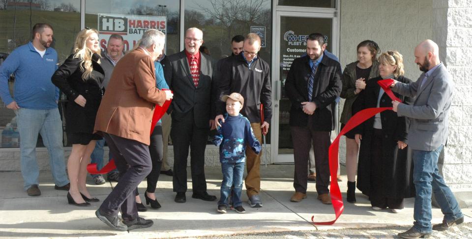 Somerset County Chamber of Commerce Executive Director Ron Aldom (foreground, at left) congratulates Henry Wheeler, center, on cutting the ribbon to officially open the new Wheeler Fleet Solutions location in Somerset. Wheeler's father, Chad, who is standing directly behind him, is president of the company.