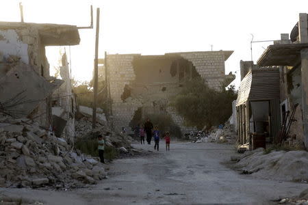 Residents walk near damaged buildings in Maarat Al-Nouman, south of Idlib, Syria, September 18, 2015. REUTERS/Khalil Ashawi