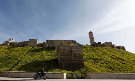 A man rides a motorbike past Aleppo's ancient citadel, in the old city of Aleppo Syria April 13, 2019. Picture taken April 13, 2019. REUTERS/Omar Sanadiki