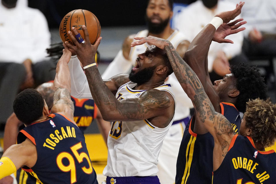 Los Angeles Lakers forward LeBron James, second from left, is fouled by Golden State Warriors guard Kelly Oubre Jr., right, while shooting as forward Juan Toscano-Anderson, left, and guard Jordan Poole defend during the first half of an NBA basketball game Sunday, Feb. 28, 2021, in Los Angeles. (AP Photo/Mark J. Terrill)