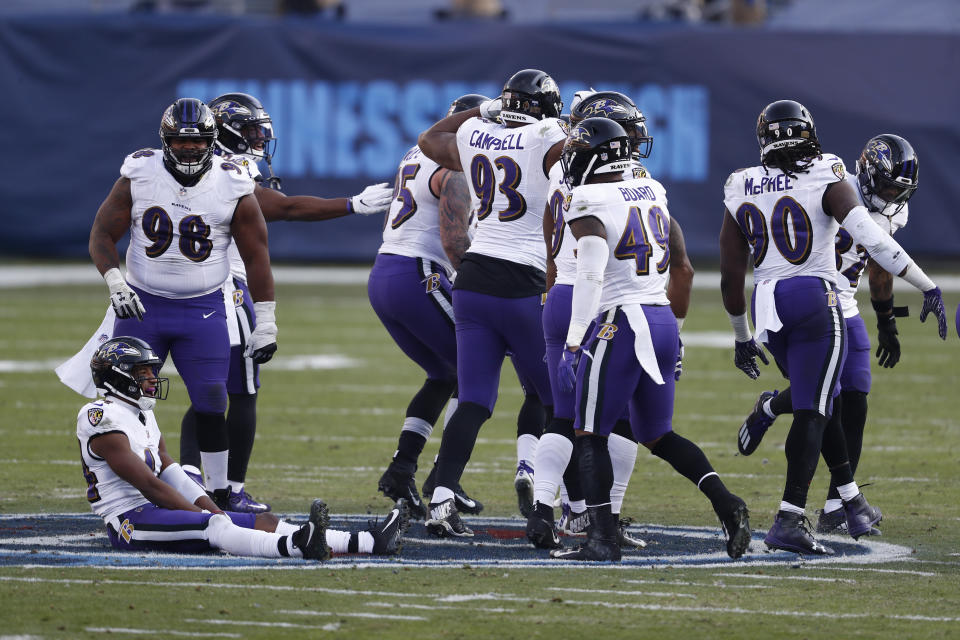 Baltimore Ravens players sit and stand on the Tennessee Titans' logo at the 50-yard line after Ravens cornerback Marcus Peters intercepted a pass against the Titans late in the fourth quarter of an NFL wild-card playoff football game Sunday, Jan. 10, 2021, in Nashville, Tenn. (AP Photo/Wade Payne)