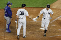 New York Yankees' DJ LeMahieu, right, is congratulated by Erik Kratz, center, after hitting a solo home run in during the eighth inning of a baseball game on Tuesday, Sept. 15, 2020, in New York. At left is Toronto Blue Jays catcher Alejandro Kirk. (AP Photo/Adam Hunger)