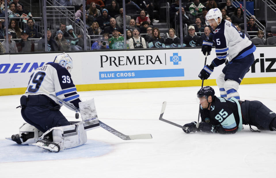 Winnipeg Jets goaltender Laurent Brossoit (39) blocks the shot by Seattle Kraken left wing Andre Burakovsky (95) with Jets' Brenden Dillon (5) behind during the first period of an NHL hockey game, Friday, March 8, 2024, in Seattle. (AP Photo/John Froschauer)