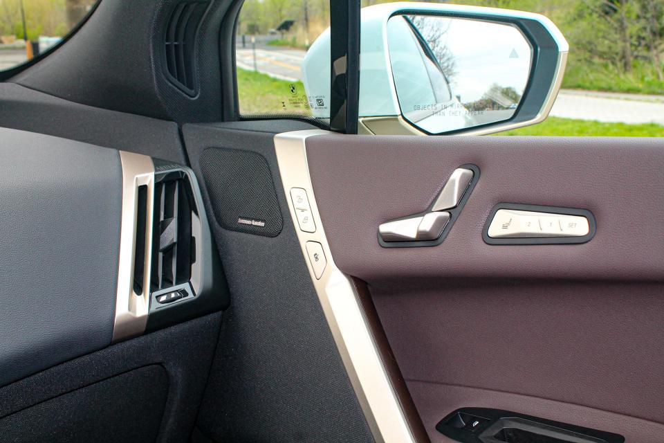 Metallic seat controls against a brown leather background in the interior of the BMW iX SUV.