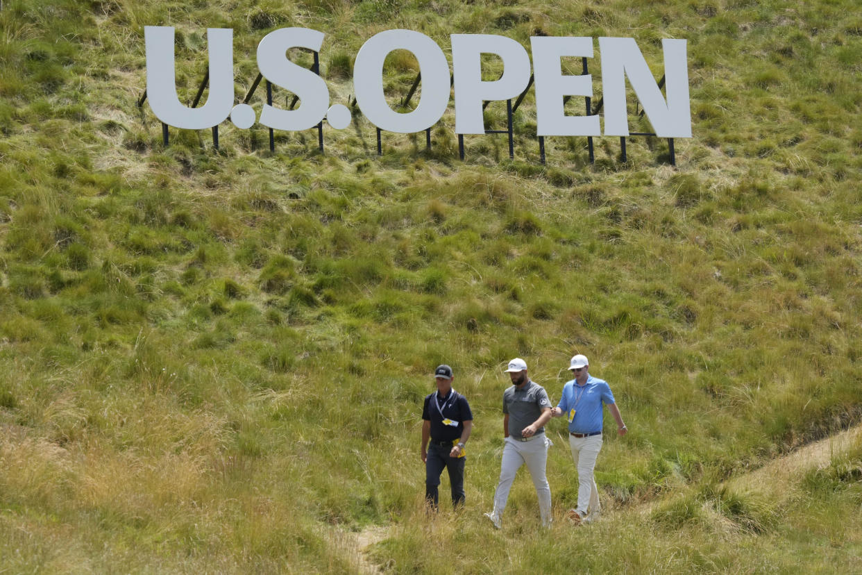 John Rahm, center, walks under a sign to the fourth green during a practice round of the U.S. Open golf tournament at Los Angeles Country Club, Monday, June 12, 2023, in Los Angeles. (AP Photo/Marcio Jose Sanchez)