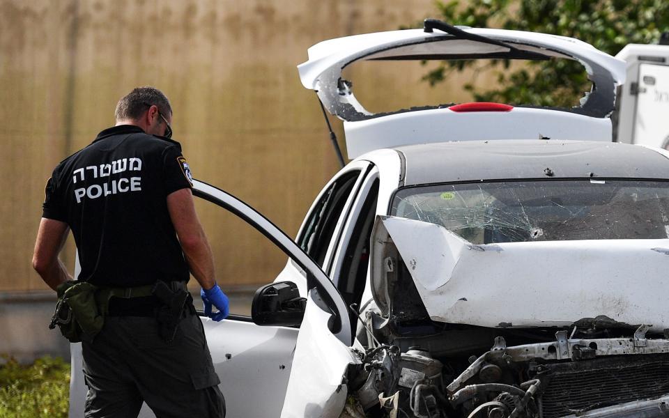 Un policía israelí revisa un automóvil dañado en la escena - GIL ELIYAHU