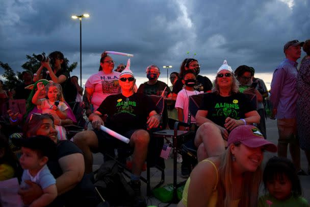PHOTO: People wearing tin foil hats watch the Abduction parade during the UFO Festival, July 2, 2021, in Roswell, New Mexico. (Patrick T. Fallon/AFP via Getty Images)