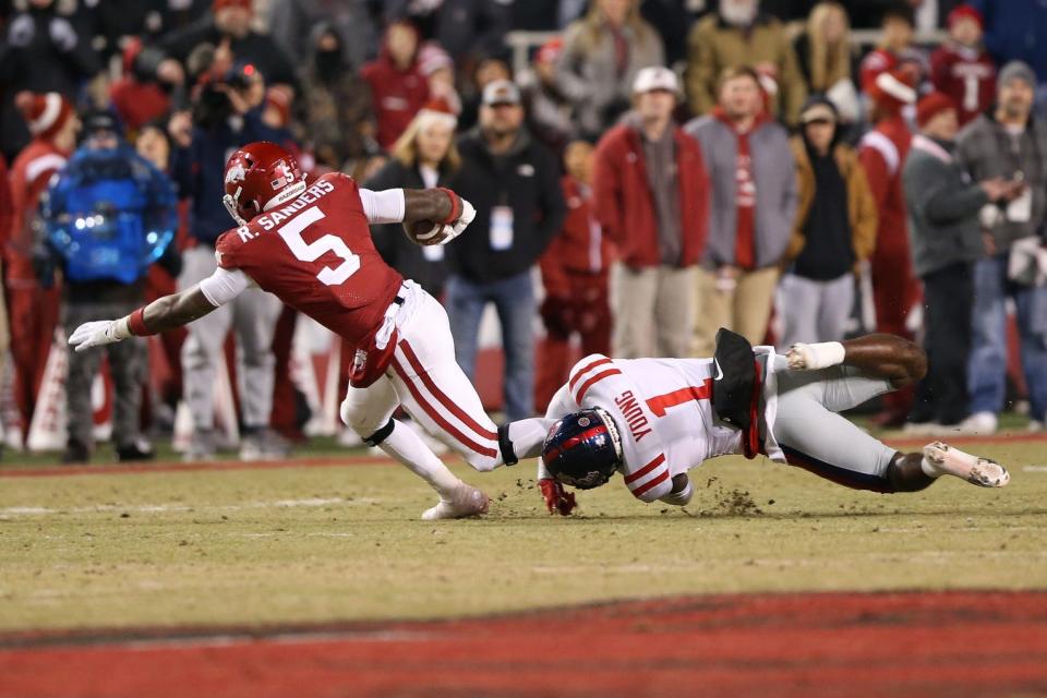 Nov 19, 2022; Fayetteville, Arkansas, USA; Arkansas Razorbacks running back Raheim Sanders (5) is tackled by Ole Miss Rebels safety Isheem Young (1) in the first quarter at Donald W. Reynolds Razorback Stadium. Mandatory Credit: Nelson Chenault-USA TODAY Sports