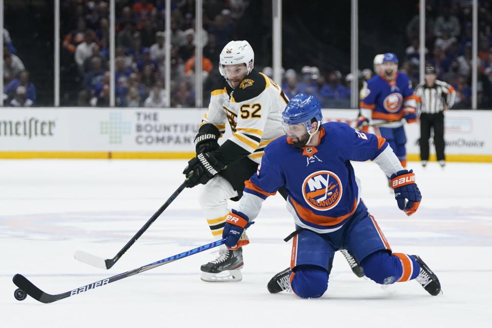 Boston Bruins' Sean Kuraly (52) and New York Islanders' Nick Leddy (2) reach for the puck during the third period of Game 3 during an NHL hockey second-round playoff series Thursday, June 3, 2021, in Uniondale, N.Y. (AP Photo/Frank Franklin II)