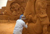 <p>A sand carver works on a sculpture during the Sand Sculpture Festival “Disney Sand Magic” in Ostend, Belgium. (Photo courtesy of Disneyland Paris) </p>