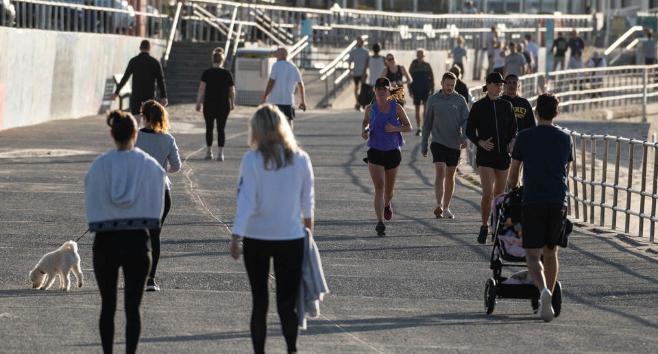 People walking and running along a beach in Sydney.