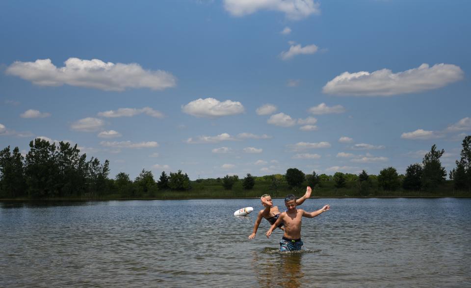 Mason Bailey of St. Johns falls into the water while riding older brother Jon's shoulders Wednesday, June 14, 2023, in the swimming area at Motz County Park in Clinton County. They were there with mom Kari and sister Alice and trying to hit the park "at least once a week" in the summertime, according to Kari.