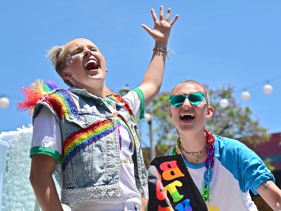 Jojo Siwa and Kylie Prew smile in rainbow outfits during a Pride parade