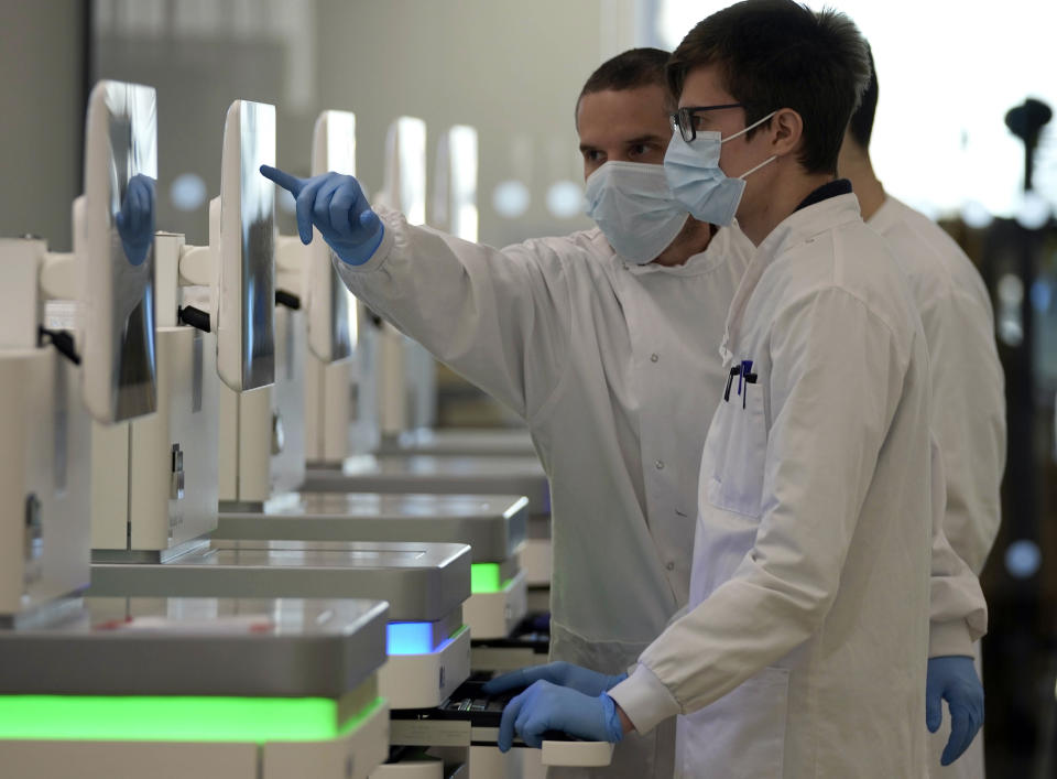 Research assistants watch the sequencing machines analyzing the genetic material of COVID-19 cases at the Wellcome Sanger Institute, Genome Campus, Hinxton, Cambridgeshire, England, on Friday, Jan. 7, 2022. The laboratory is one example of how British scientists have industrialized the process of genomic sequencing during the pandemic, cutting the time and cost needed to generate a unique genetic fingerprint for each coronavirus case analyzed. (AP Photo/Frank Augstein)