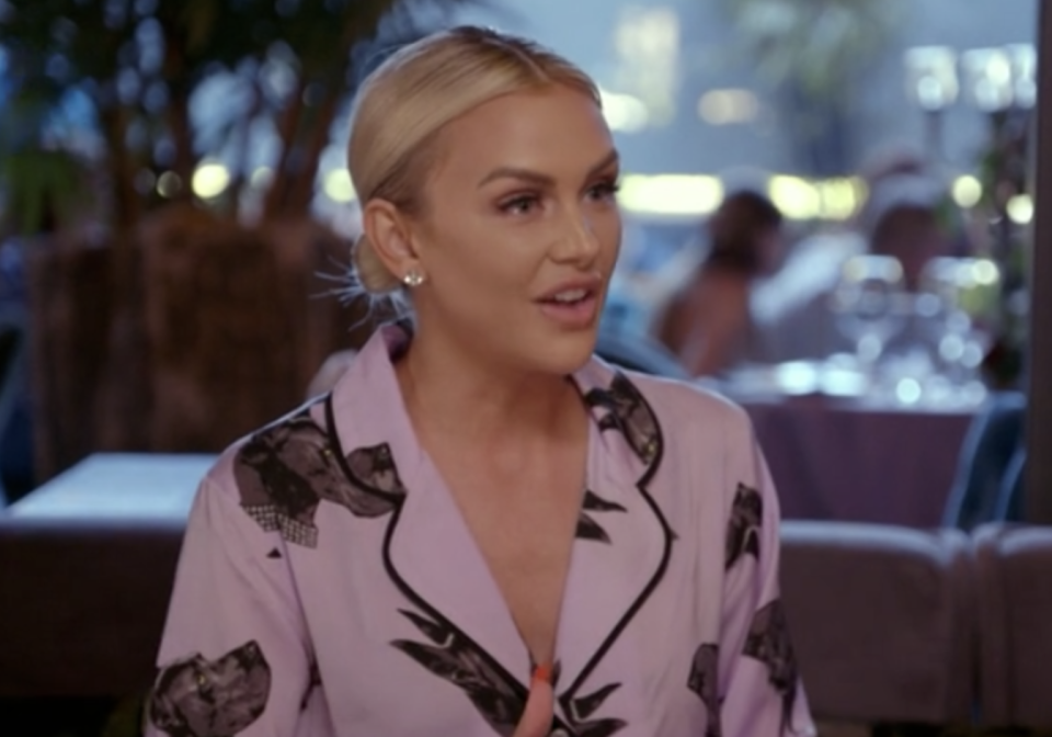 A close up of Lala talking in a bar, she's wearing pink satin pyjamas with dog faces on them