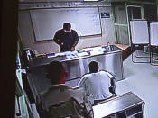 Some of the most compliant captives at the prison camps are allowed to study in Arabic or Pashto with a contract Defense Department instructor at Guantanamo Bay, Cuba. In this session, viewed by closed circuit, two guards hover near an Arab man, shackled to the floor of a classroom, while an instructor who tells his students to call him "Adam" teaches formal Arabic grammar. (Carol Rosenberg/Miami Herald/MCT)
