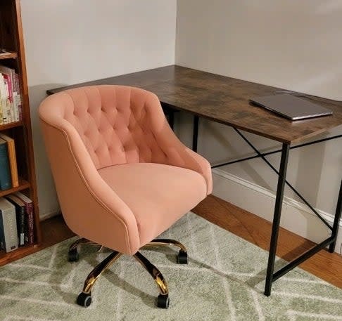 A pink tufted office chair with gold accents beside a desk