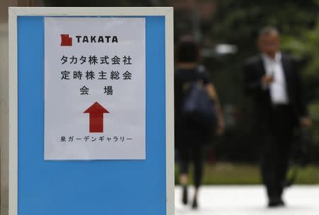 A man walks behind a sign board of Japanese auto parts maker Takata Corp's Annual General Meeting in Tokyo June 26, 2014. REUTERS/Yuya Shino