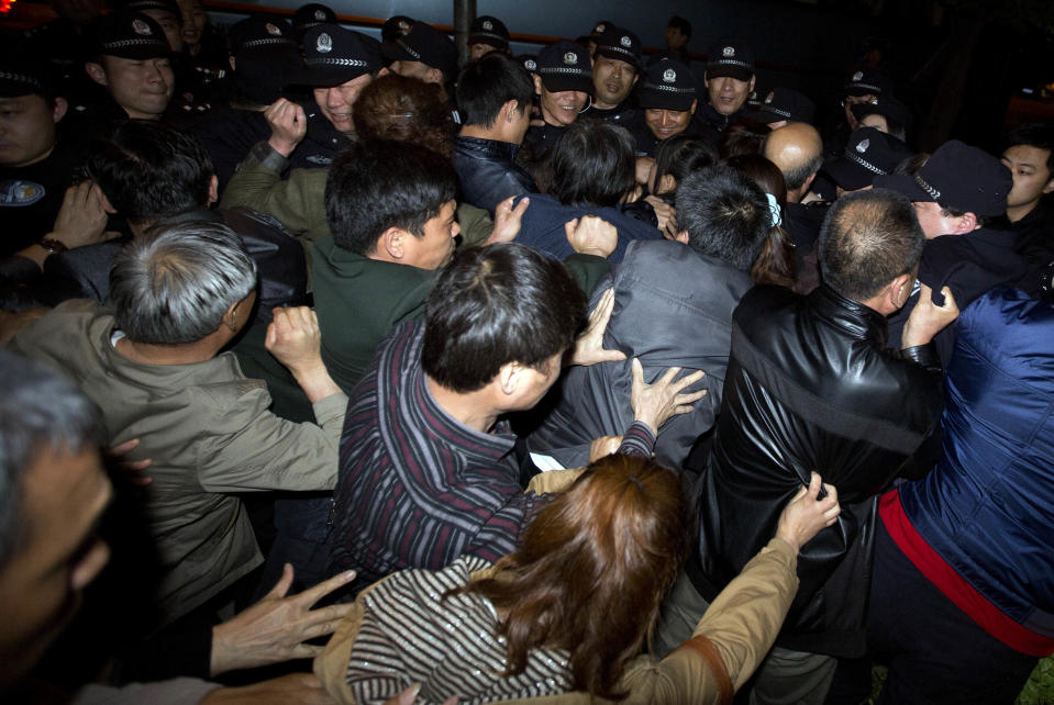 Relatives of Chinese passengers onboard the Malaysia Airlines MH370 push through a police line to march to the Malaysian embassy from a hotel in Beijing, China, Thursday, April 24, 2014. Angry relatives who had been waiting for more than 8 hours in vain for a Malaysia embassy representative to attend their daily meeting marched to the Malaysia embassy and protested through the night. (AP Photo/Ng Han Guan)